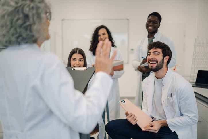 Four students with notebooks speaking to each other around a conference table