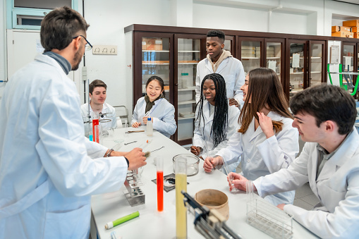 Faculty member and students in lab coats around a table in a medical facility